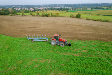 Red tractor on the field near the railway. Agricultural industry. View from above.