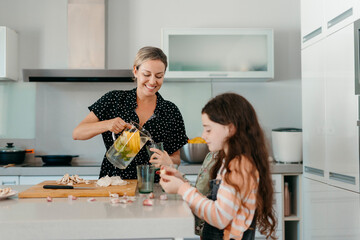 Mother serving lemonade to her daughter in kitchen