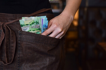 Server using pockets of her apron to keep cash money tips