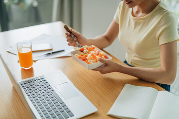 Young beautiful businesswoman at working place, eating vegetable