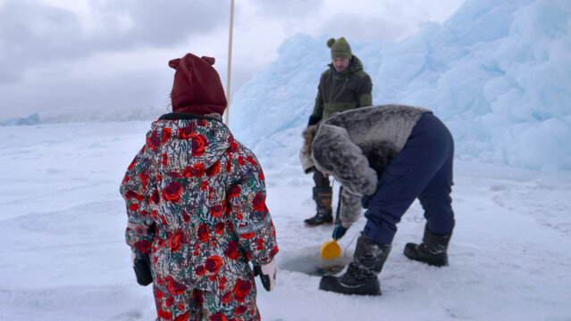 Arctic Greenland seaice traditional life - girl watches seal hunters