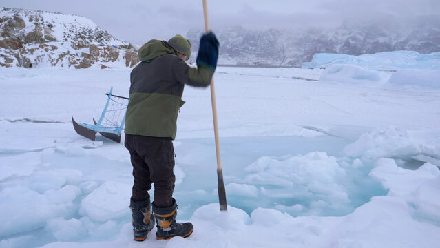 Arctic seal hunter tests safety of sea ice tide hinge with spear