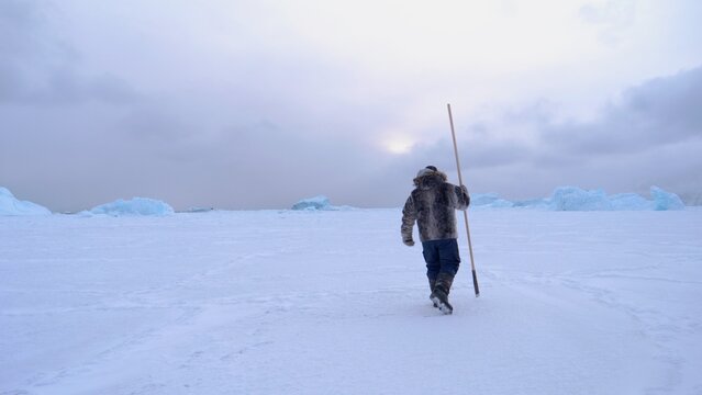 Greenlandic hunter tests if sea ice is frozen, early winter