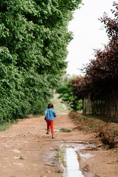 Unrecognizable girl running on dirty road