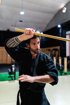 Martial artist practicing with stick in gym