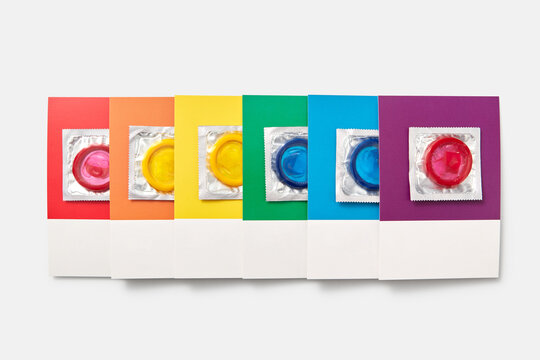 Multicolored condoms and color swatches on white background.