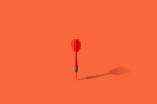 Dart with shadow on red background.