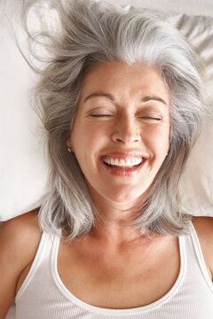 Portrait of mature woman laughing in bed