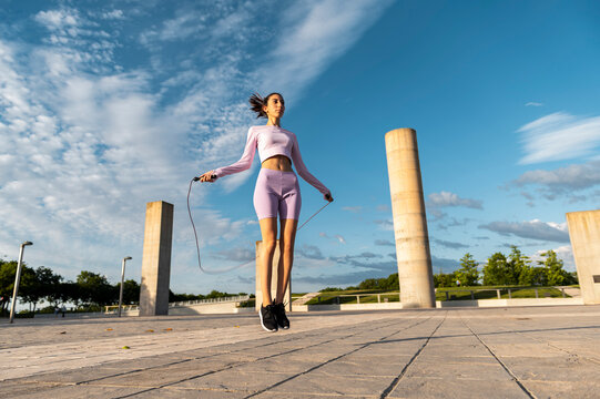 Slim woman in sporty clothes jumping rope 