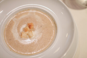 Creamy white soup with bread on top in white plate. Italian and French food. Dinner table concept.