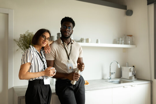 Mixed couple having coffee at office kitchen