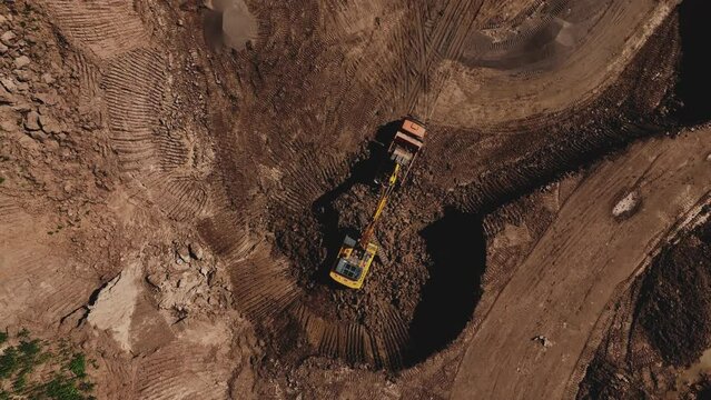 Excavator during clay mining.  mining in open pit. Aerial view of an opencast for the extraction of clay and limestone. Brick and Tile. Excavator loads clay in dump truck in quarry. 