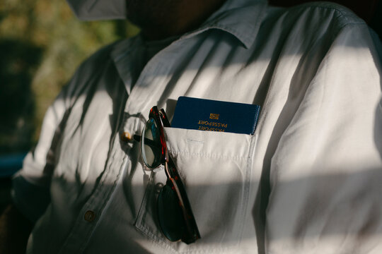 Passport and sunglasses in man's shirt pocket in sunlight