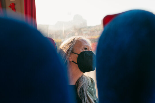 Senior woman traveling in bus with face-mask