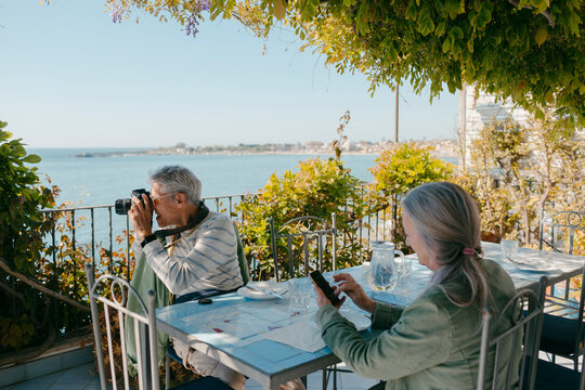 Senior couple of tourists sitting at restaurant terrace enjoying views