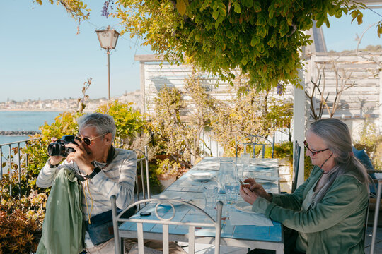 Senior couple of tourists sitting at restaurant terrace enjoying views