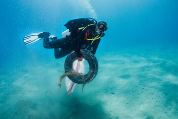Egyptian man carrying a tire and trash collected at ocean cleanup