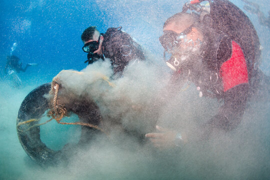 Scuba Divers at Ocean Cleanup Removing Tire from the Sea