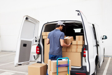 Delivery man loading van on parking lot