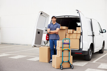 Confident delivery man near van with parcels
