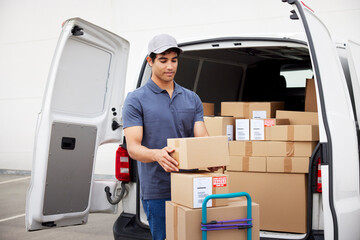 Delivery man stacking parcels on trolley