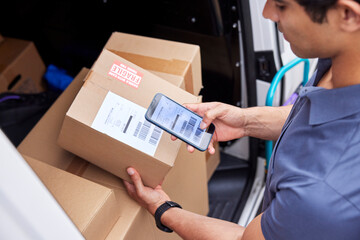 Cropped delivery man scanning barcode on parcel