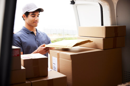 Young Hispanic courier loading parcels into van