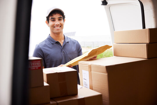 Happy delivery man loading parcels into van