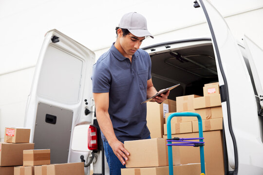 Hispanic courier with tablet taking parcel from trolley