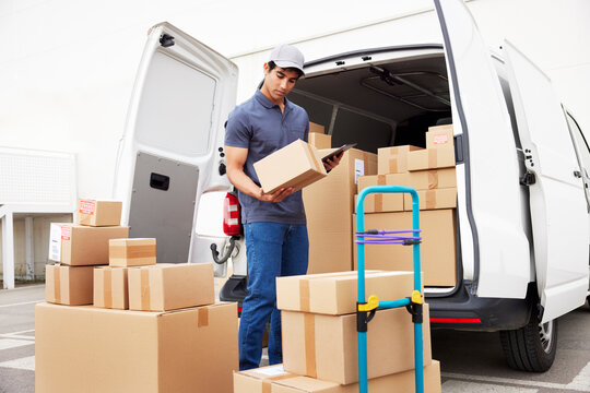 Delivery man reading address near van