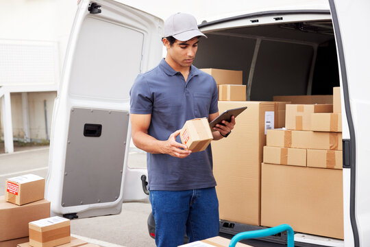 Delivery man checking parcel near van