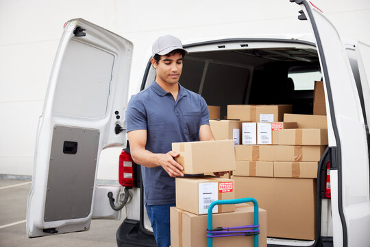 Delivery man stacking parcels on trolley