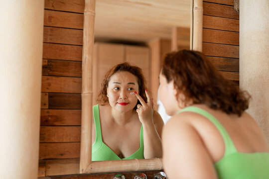 Asian plus-size woman after shower looking in the mirror