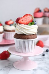 Delicious cupcake with cream and berries on white marble table