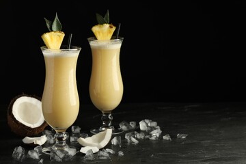 Tasty Pina Colada cocktails on dark table, space for text - obrazy, fototapety, plakaty