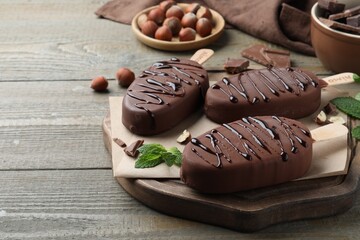 Delicious glazed ice cream bars, nuts and mint on wooden table
