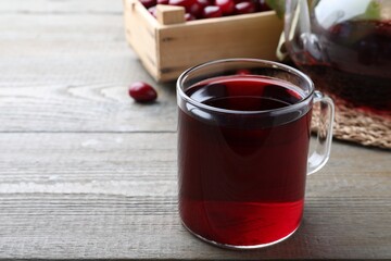 Glass cup of fresh dogwood tea on wooden table. Space for text