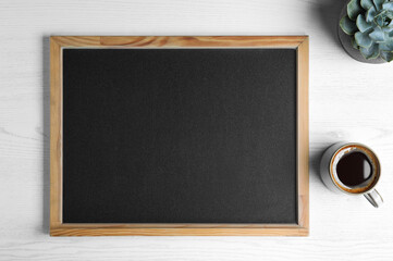 Clean small chalkboard, coffee and plant on white wooden table, flat lay