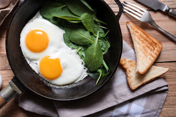 Delicious fried egg with spinach served on wooden table, flat lay
