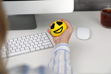 Woman squeezing antistress ball at workplace, closeup
