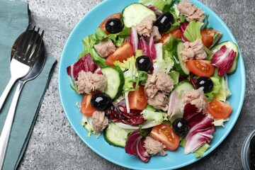 Plate of delicious salad with canned tuna and vegetables served on grey table, flat lay
