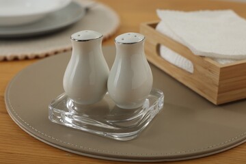 White ceramic salt and pepper shakers on wooden table