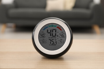 Digital hygrometer with thermometer on wooden table in room - obrazy, fototapety, plakaty