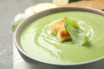 Tasty homemade zucchini cream soup in bowl on table, closeup