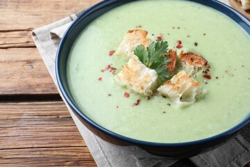 Delicious asparagus soup with croutons on wooden table, closeup