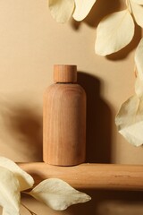 Fototapeta na wymiar Wooden bottle of cosmetic product and dried leaves on dark beige background