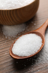 Fototapeta na wymiar Granulated sugar on wooden table, closeup view