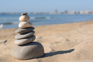 Fototapeta na wymiar Stack of stones on sandy beach, space for text