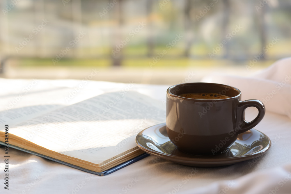 Wall mural Aromatic morning coffee and open book on bed indoors