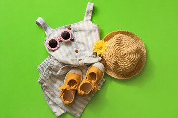 Stylish child clothes, shoes and accessories on green background, flat lay
